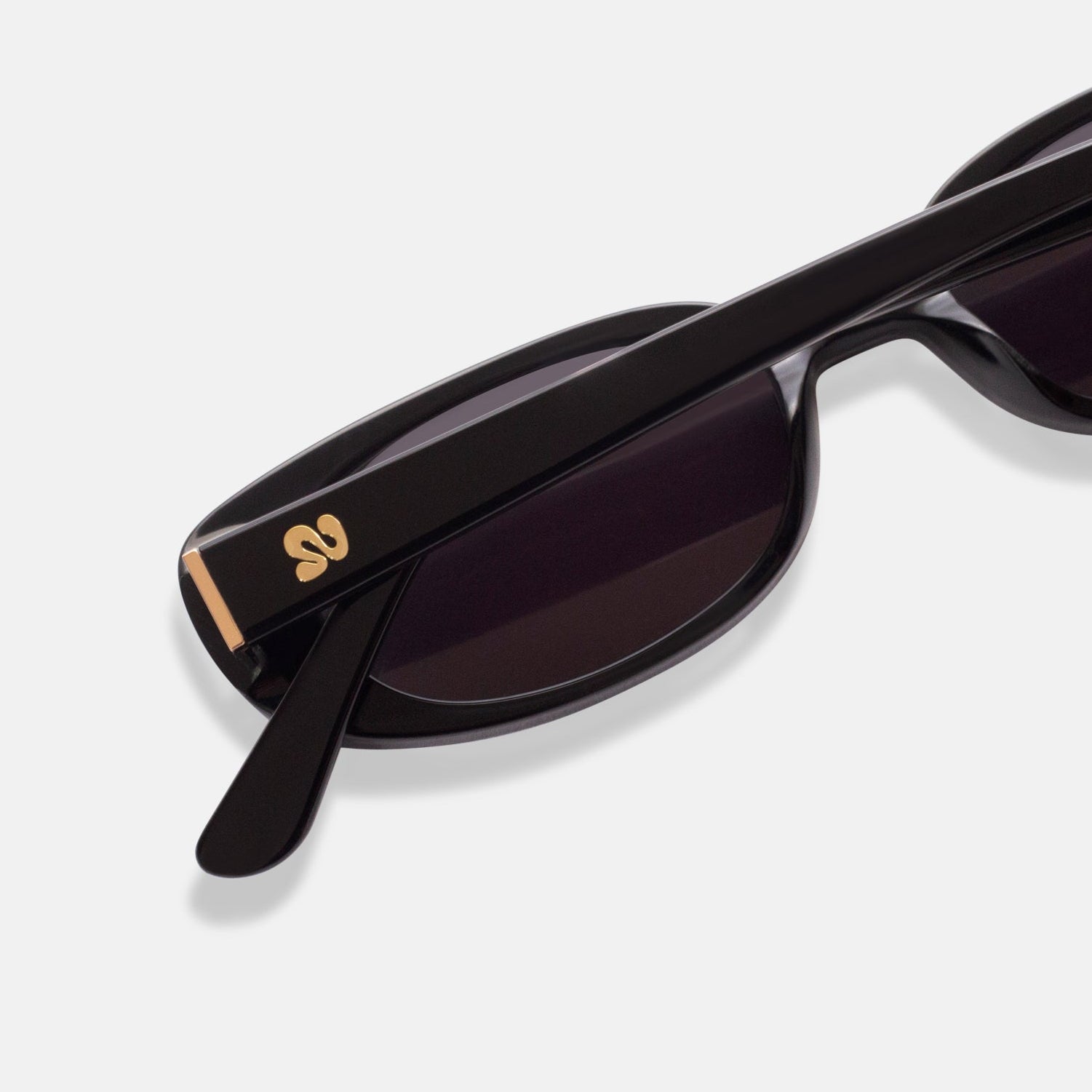 Close-up of Isla Sunwear logo on black oval sunglasses, designed for smaller faces.