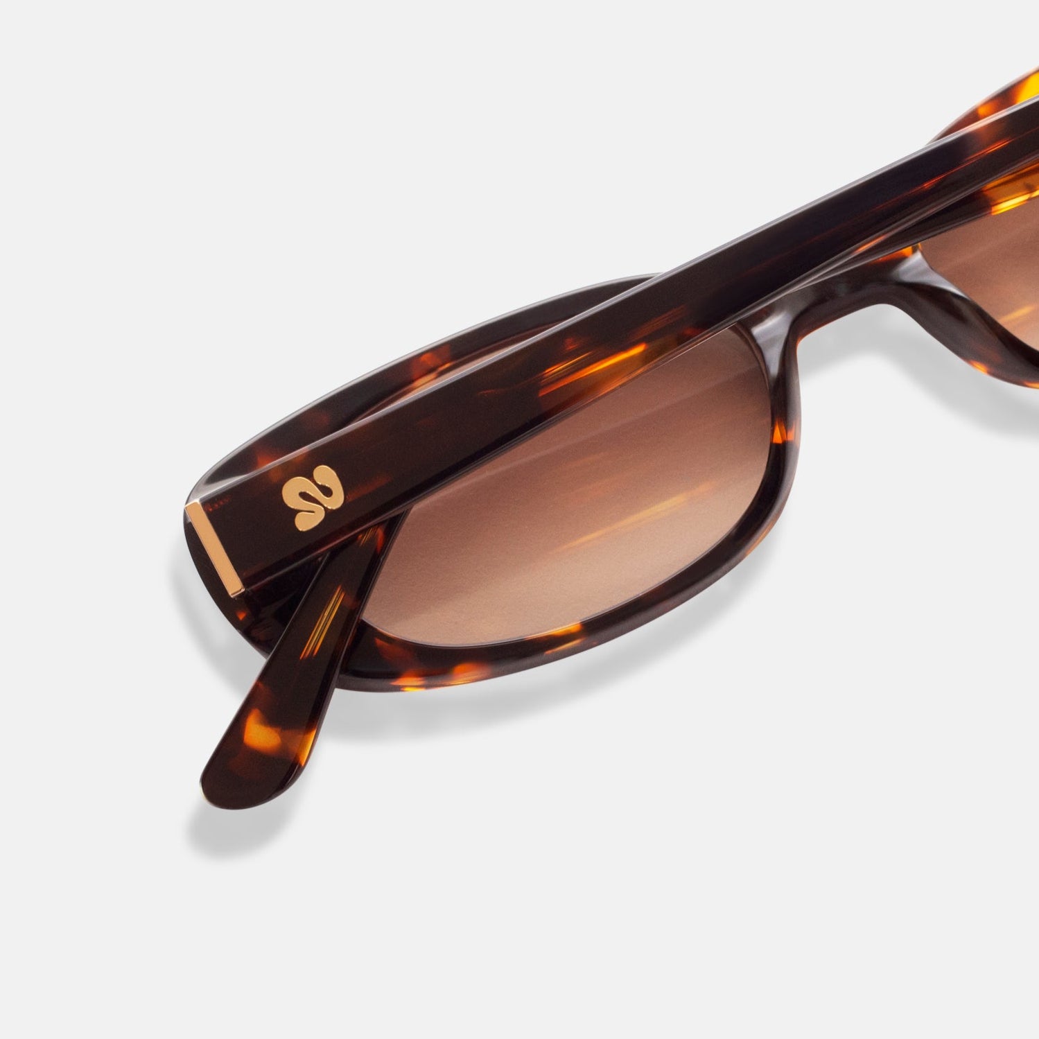 Close-up of Isla Sunwear logo on tortoise oval sunglasses, designed for smaller faces.