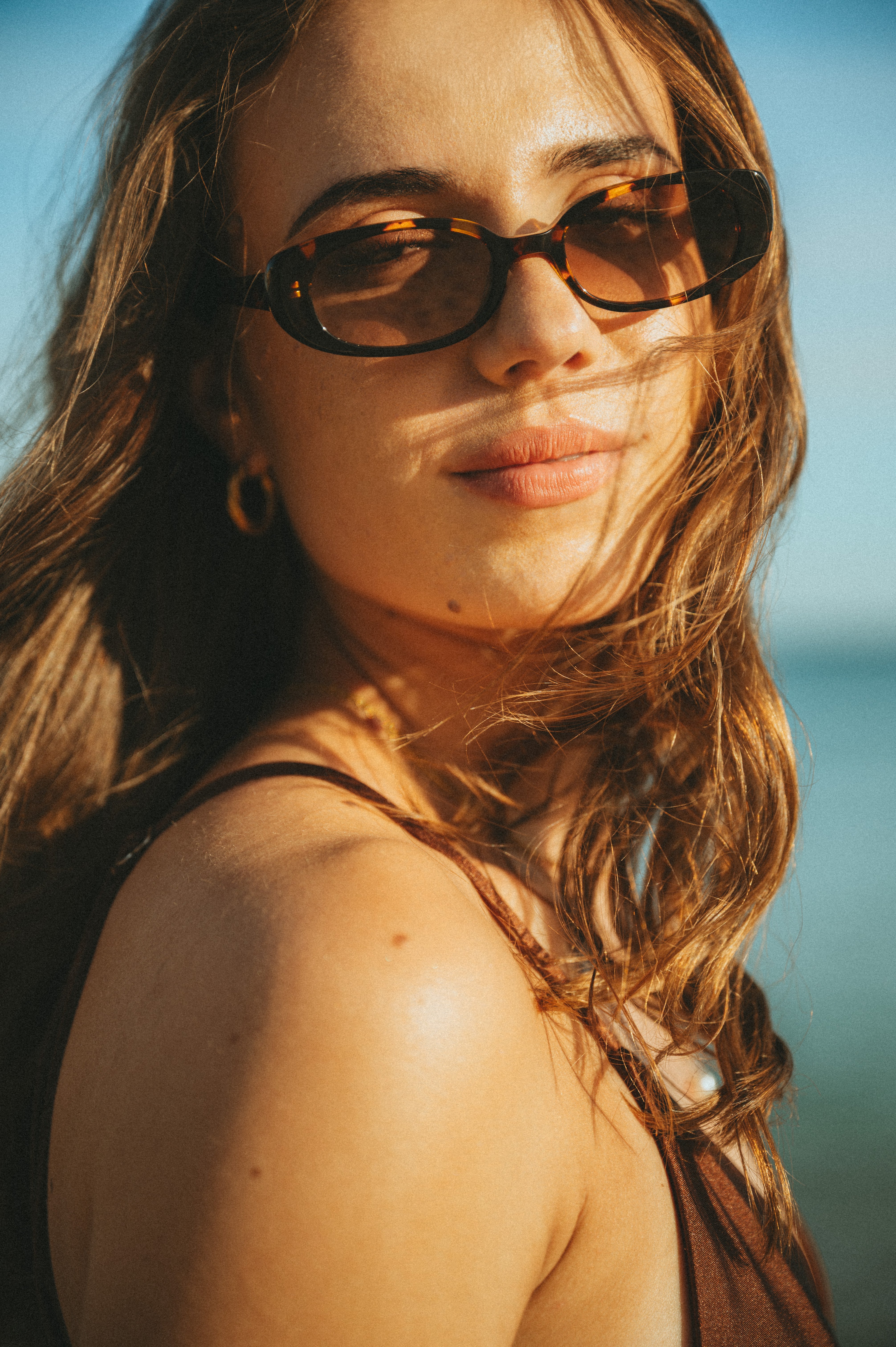 Portrait of a woman wearing Isla Sunwear tortoise oval sunglasses, designed for smaller faces.