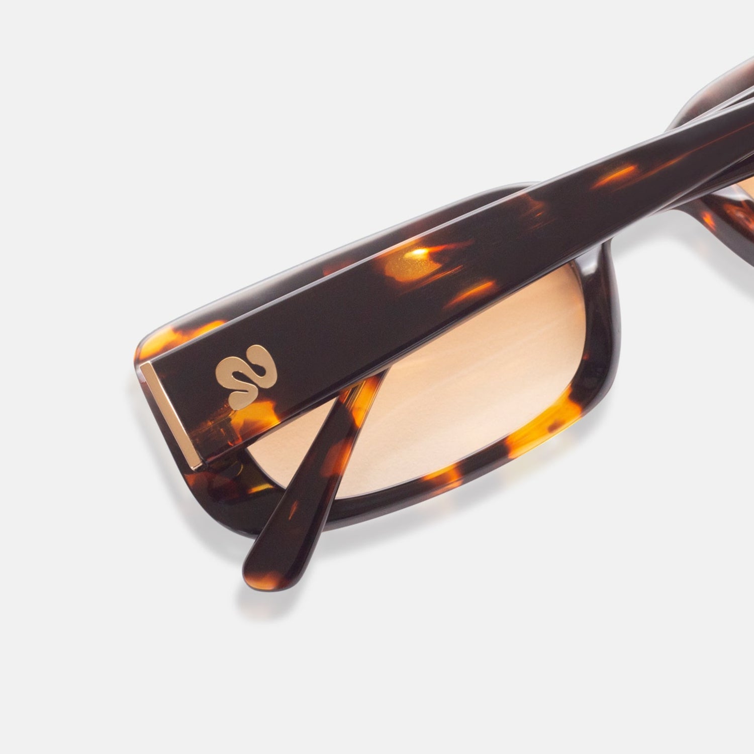 Close-up of Isla Sunwear logo on tortoise rectangular sunglasses, designed for smaller faces.
