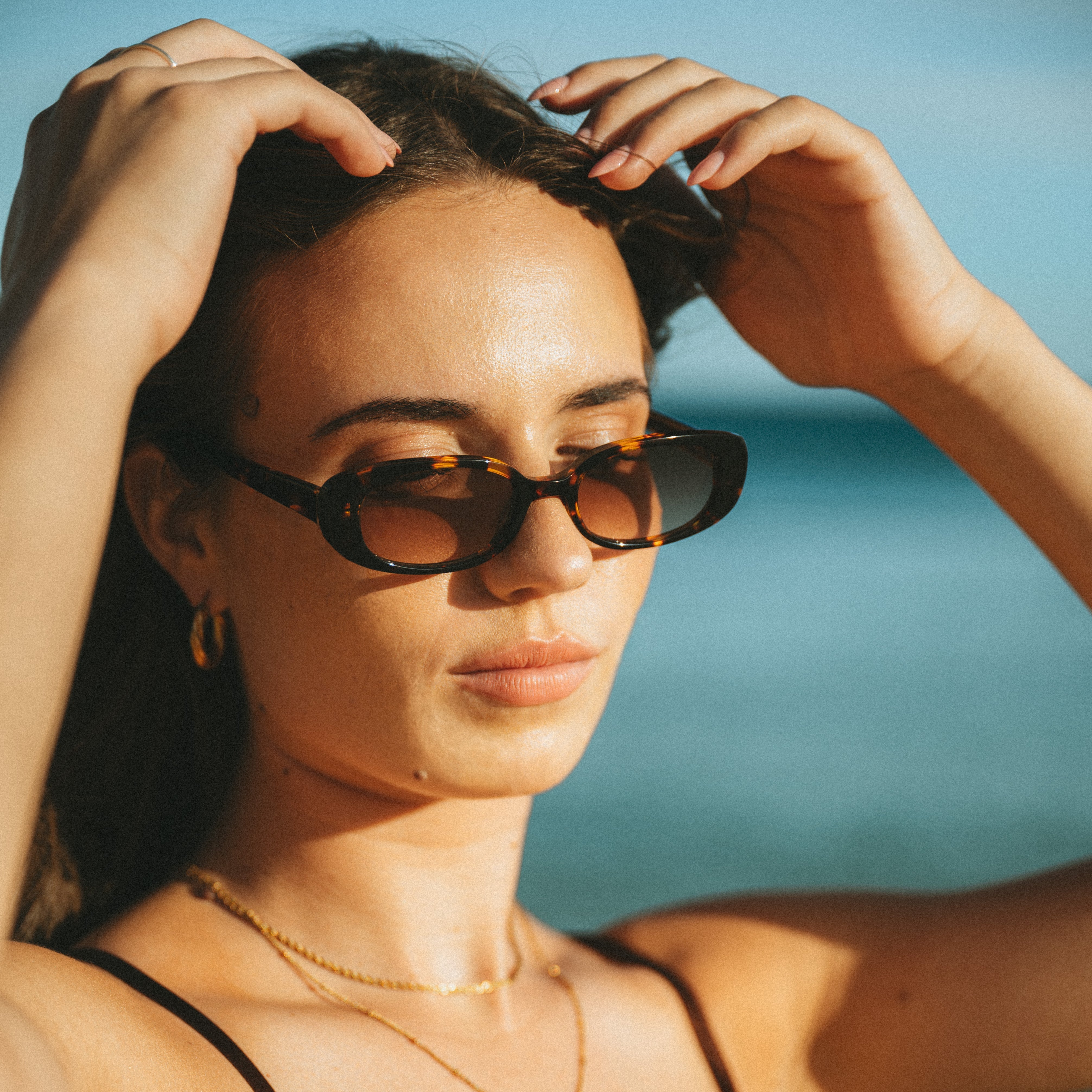Closeup portrait of a woman wearing Isla Sunwear tortoise oval sunglasses, designed for smaller faces.